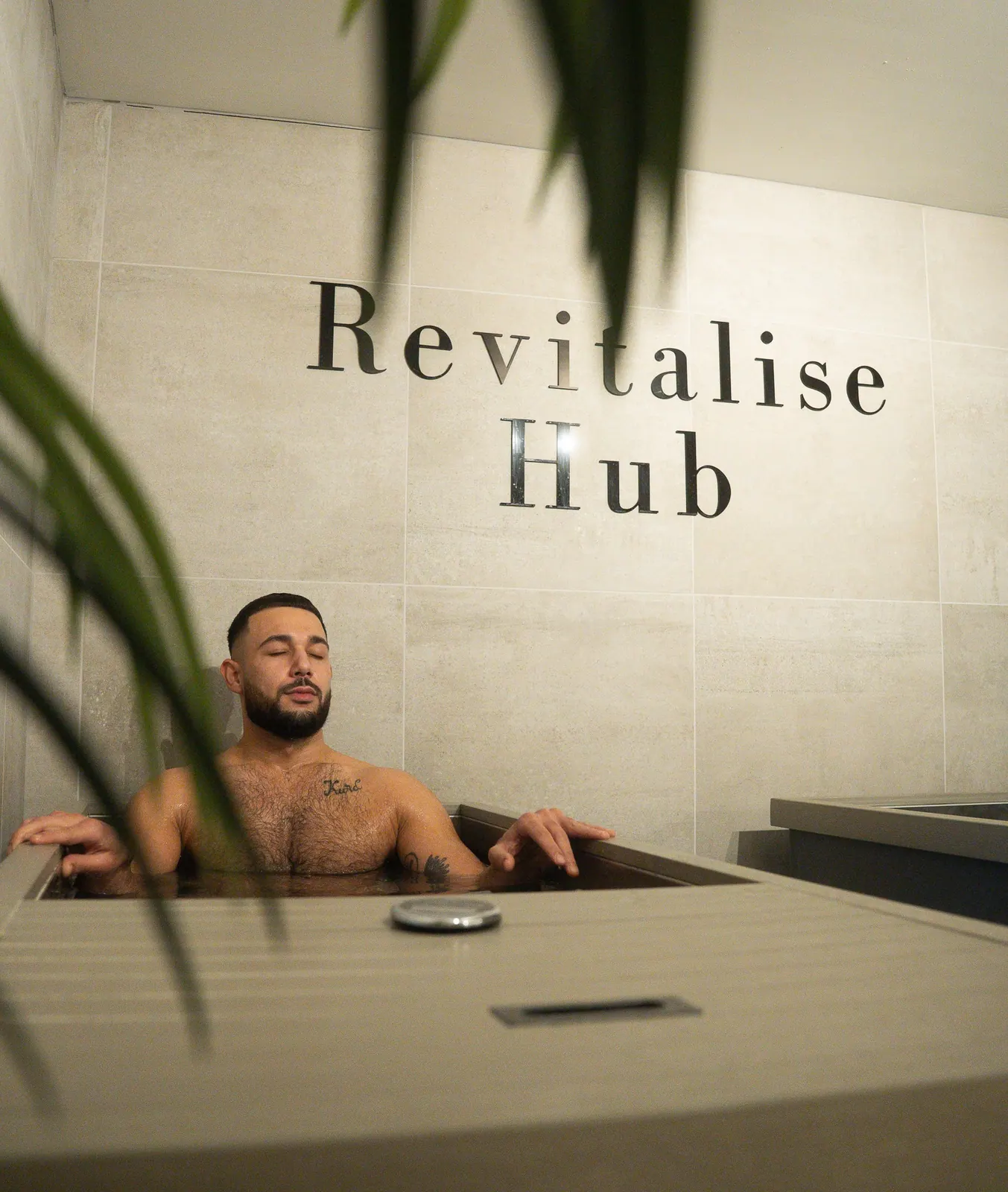 A guest sitting in an ice bath beneath the Revitalise Hub sign